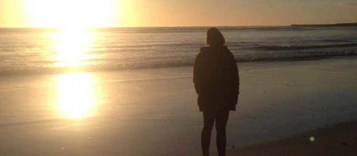 Woman staring out over the ocean into the sun set, wondering how to find hope when all seems lost